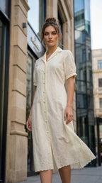 Woman wearing a white dress standing on a city street.