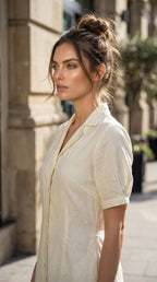 Woman wearing a light-colored shirt standing on a street with buildings in the background