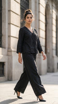 Woman in a black outfit walking on a city street.