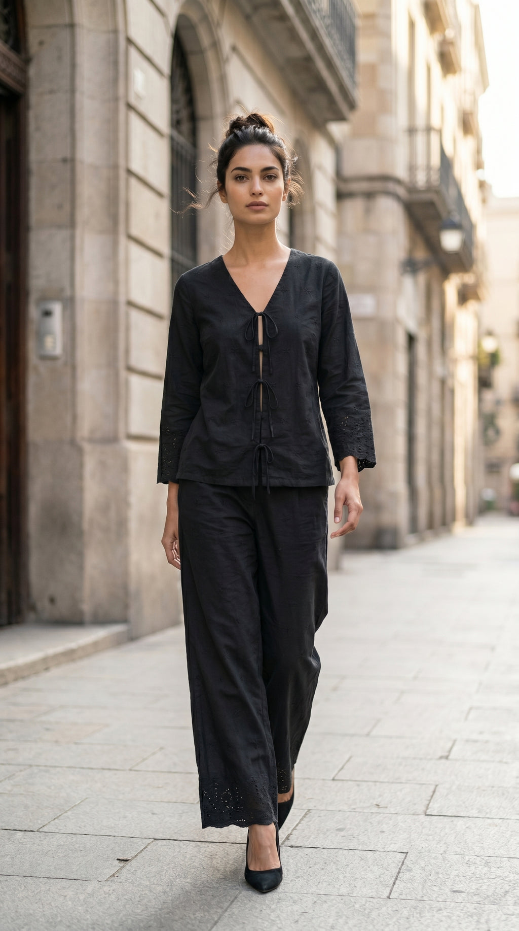 Woman in a black outfit walking down a city street.