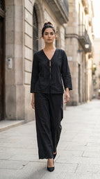 Woman in a black outfit walking down a city street.