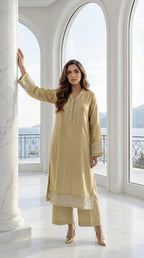 Woman in a light green traditional outfit standing in a bright, elegant room with large windows.