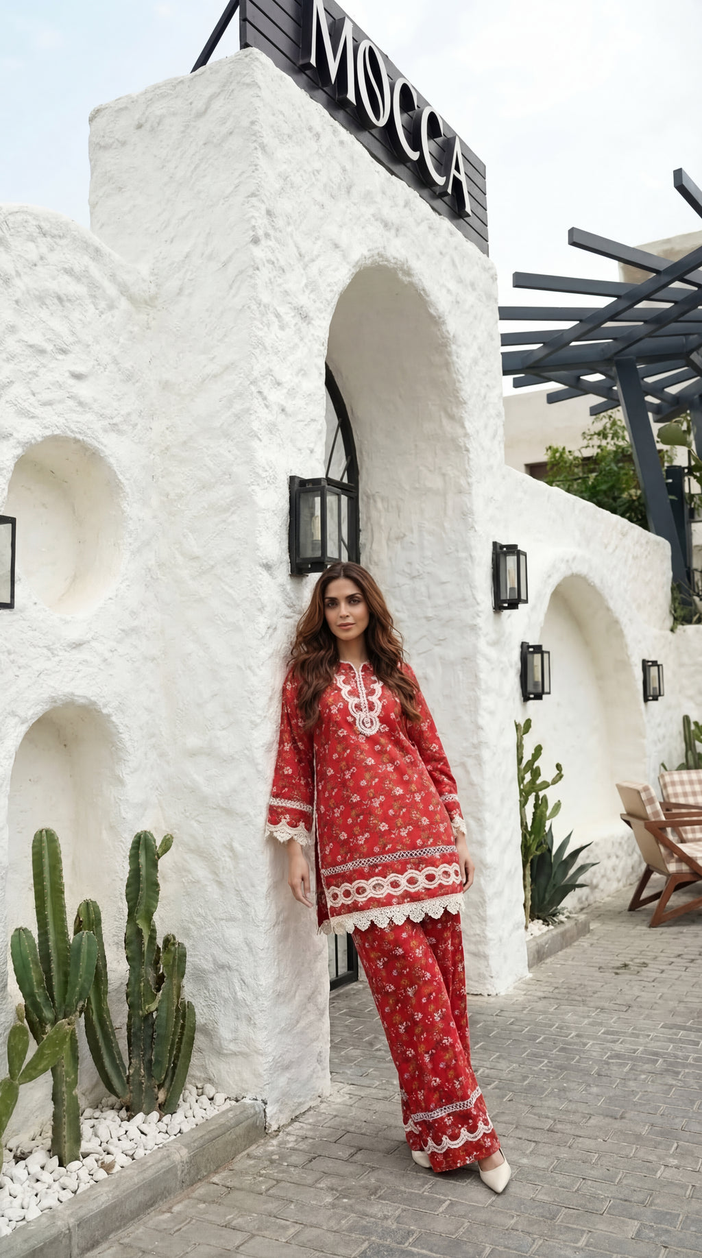 Woman in a red outfit standing in front of a white architectural structure with 'Mocca' cafe