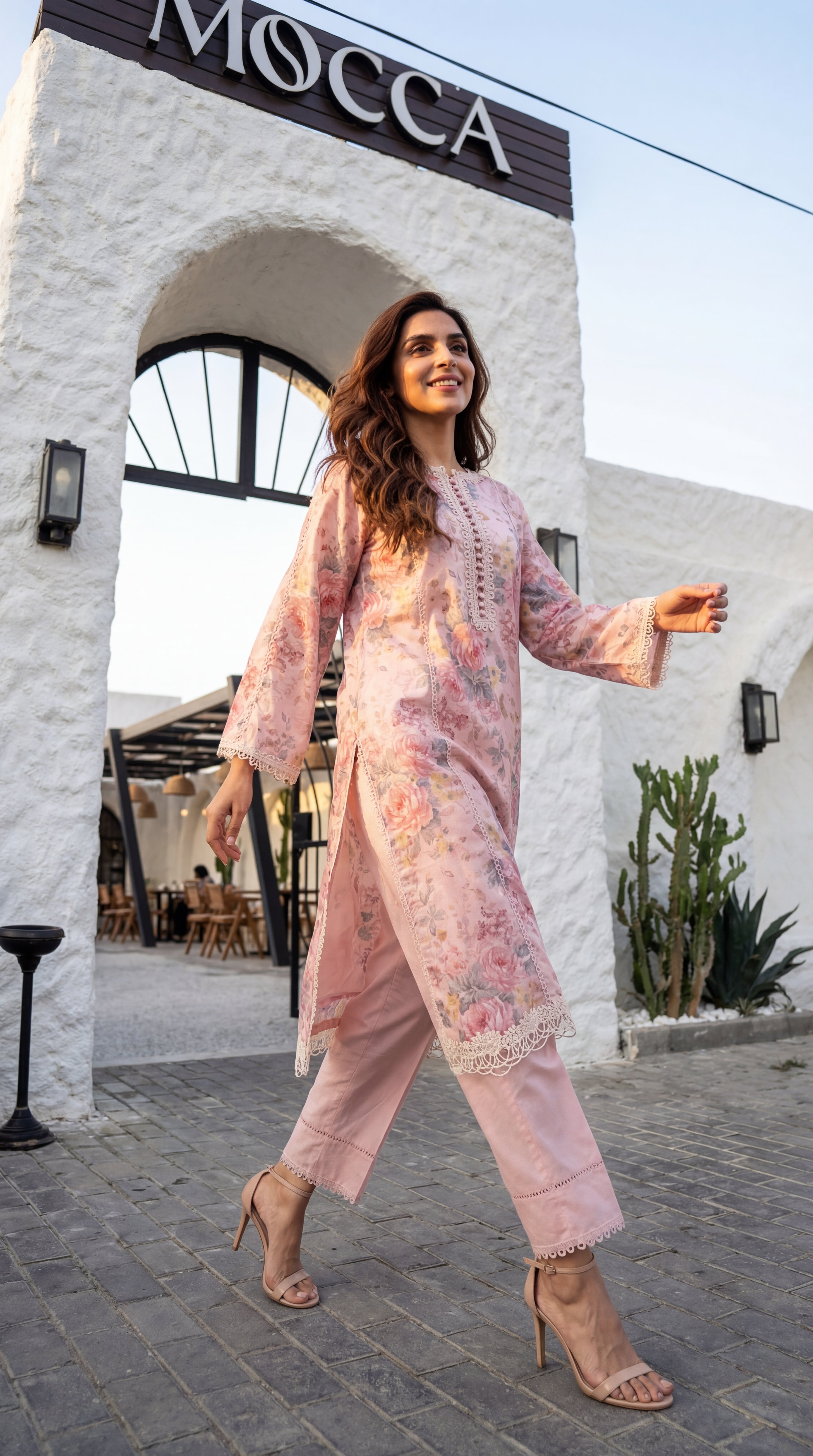 Woman in a pink floral outfit walking in front of a building with 'MOCCA' cafe Baku