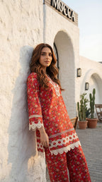 Woman in a red floral dress standing against a white wall with 'Moschino' branding.