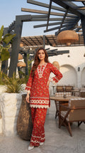 Woman in a red outfit with white embroidery standing outdoors.