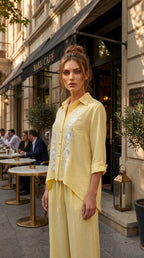 Woman in a yellow outfit standing in front of a cafe