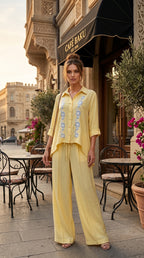 Woman in a yellow outfit standing in front of a cafe named 'Cafe Baku'.