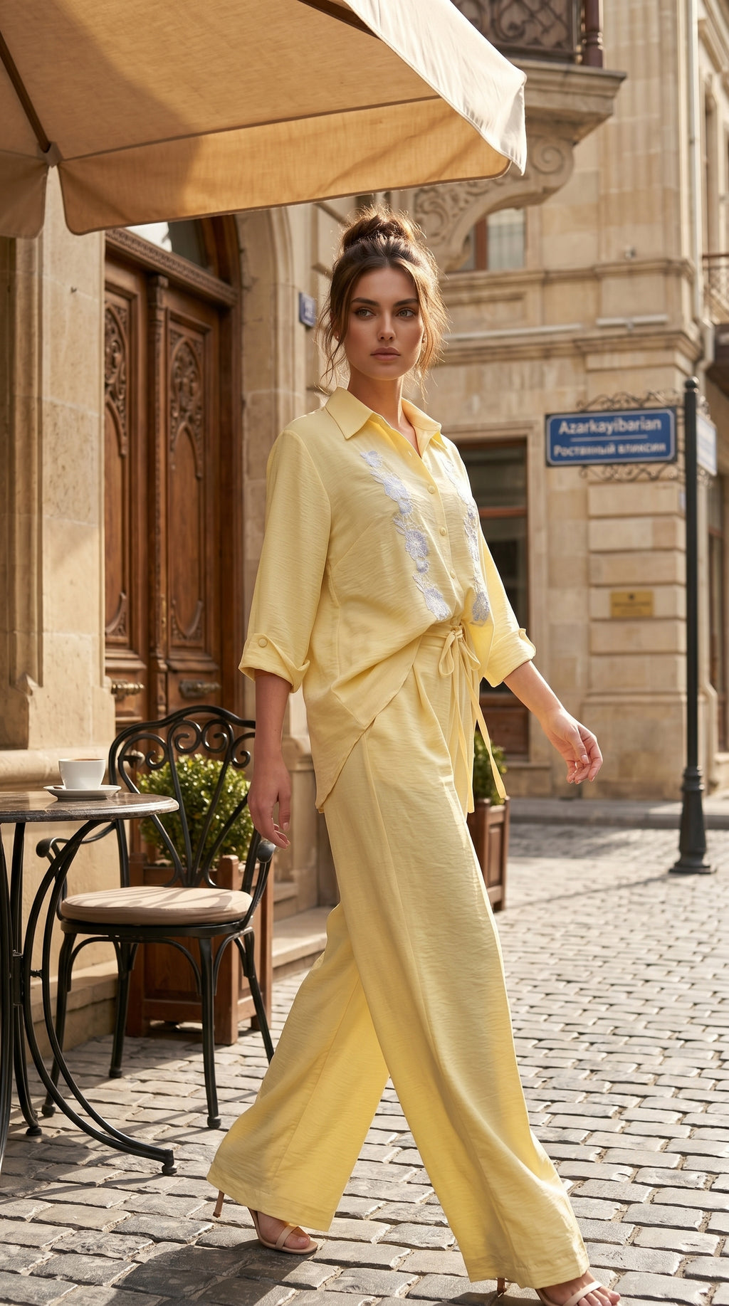 Woman in a yellow outfit walking on a street with a cafe in the background