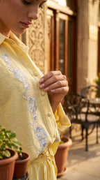 Woman wearing a yellow dress with floral embroidery in an outdoor setting